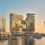 Modern high-rise buildings near a marina during sunset.