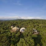Aerial view of The Highlands Lodge surrounded by dense green forest, with unique circular and dome-shaped structures.