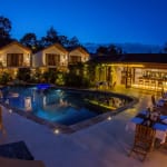 Luxushotel mit beleuchtetem Pool und modernen Hütten bei Nacht in Ruanda.