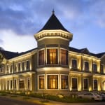 Elegant hotel building with turret and warm exterior lighting in the evening, located in San Jose, Costa Rica.