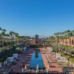 Luxurious pool area with palm trees and loungers in a sunny resort setting.