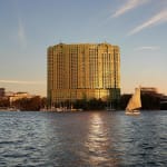 Das Four Seasons Hotel Cairo am Nile Plaza steht hoch am Nil während der goldenen Stunde, mit seiner Glasfassade, die das warme Sonnenlicht widerspiegelt.