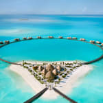 Luxushotel mit Wasserbungalows und einem großen kreisförmigen Pool am Strand am Roten Meer.