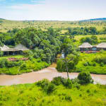 Luxury tents of a Salas Camp near a river, surrounded by lush greenery and open plains in Masai Mara.