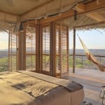 View from a guest room at Jabali Ridge showing a hammock on the balcony and scenic landscape beyond.
