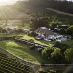 Ein luxuriöses Anwesen mit Pool und umgebender grüner Landschaft in einer Hügelregion, Sonnenstrahlen scheinen auf das Gelände.