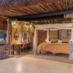 Innenraum eines rustikalen Safari-Zimmers mit Himmelbett, Sitzecke mit Schaukel und warmem Licht