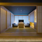 Eine traditionelle japanische Lounge mit niedrigen Sitzmöbeln, Shoji-Schiebetüren und gedämpfter Beleuchtung in einem Hotel.