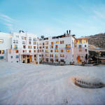 Das Moevenpick Resort Petra mit moderner weißer Architektur vor einem Hügel unter blauem Himmel.
