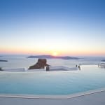 Infinity-Pool mit Blick auf den Ozean bei Sonnenuntergang auf Santorini.