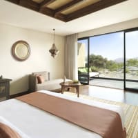 Ein geräumiges Hotelzimmer mit Balkonblick auf die Natur und Berge in Oman.