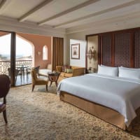 Luxuriöses Hotelzimmer mit großem Bett, Sitzbereich und Balkon mit Aussicht.