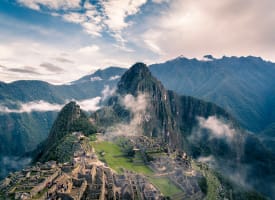 Luftaufnahme der antiken Inkastadt Machu Picchu, umgeben von Bergen und Wolken in Peru.