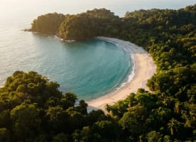 Hufeisenförmige Bucht von Playa Manuel Antonio mit türkisem Wasser und Regenwald im Morgenlicht