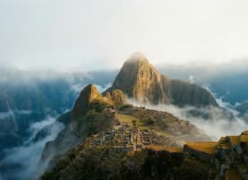 Machu Picchu im Morgengrauen — Inka-Ruinen im Nebel mit Huayna Picchu im warmen Sonnenlicht