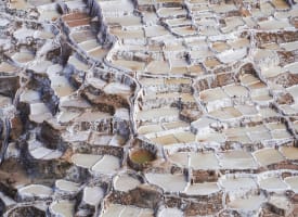 Terrassierte Salztümpel an einem Hang in Maras, Cusco, Peru, mit verschiedenen Stadien der Salzkrustenbildung.