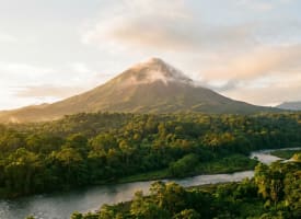 Der Vulkan Arenal hinter tropischem Regenwald in Costa Rica im goldenen Morgenlicht
