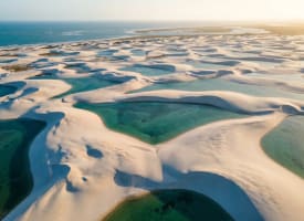 Luftaufnahme der Lençóis Maranhenses in Brasilien mit weißen Dünen und türkisen Süßwasserlagunen im goldenen Abendlicht