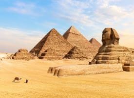 The Great Pyramids of Giza and the Sphinx located in a desert landscape under a blue sky.