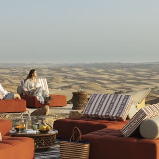 Luxurious outdoor seating area with cushions and tables overlooking desert landscape