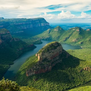 Eine spektakuläre Aussicht auf den Blyde River Canyon. Der Fluss windet sich durch die tiefen, grünen Täler, umgeben von majestätischen Felsformationen und üppigen Wäldern.