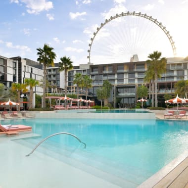 Luxus-Hotelpoolbereich im Banyan Tree Dubai mit Riesenrad im Hintergrund bei teilweise bewölktem Himmel.