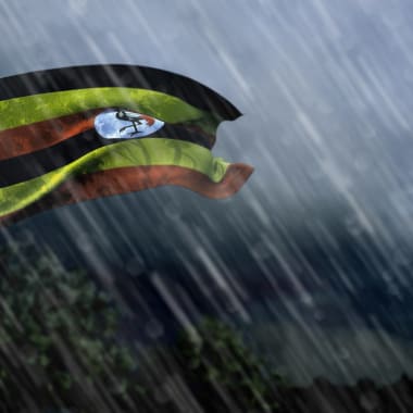 Die Fahne von Uganda ist im stürmischen Regenwetter zusehen 