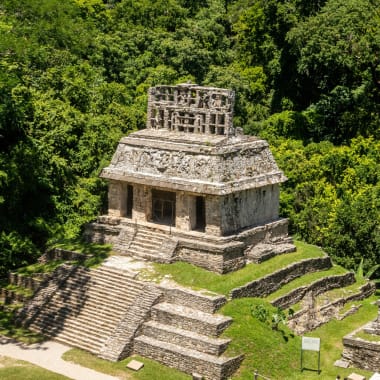 Antike Stein-Tempelruinen umgeben von dichtem grünem Dschungel in Palenque, Chiapas, Mexiko.