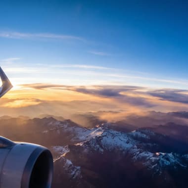 Flug nach Kolumbien - Blick aus dem Flugzeugfenster auf die schneebedeckten Gipfel der kolumbianischen Anden bei Sonnenaufgang