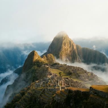 Machu Picchu im Morgengrauen — Inka-Ruinen im Nebel mit Huayna Picchu im warmen Sonnenlicht