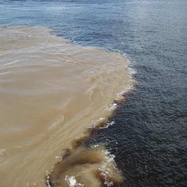 A river meeting where two different colored waters converge in Manaus, Amazonas, Brazil.