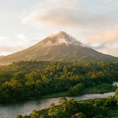 Der Vulkan Arenal hinter tropischem Regenwald in Costa Rica im goldenen Morgenlicht