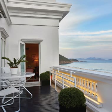 A balcony with white furniture overlooking the beach and ocean in Rio de Janeiro, Brazil.
