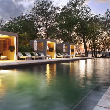 Luxury outdoor pool area at sunset with cabanas and lounge chairs in Costa Rica