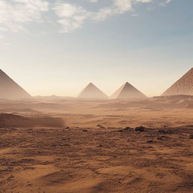 Alte ägyptische Pyramiden ragen über eine Wüstenlandschaft bei Sonnenuntergang.