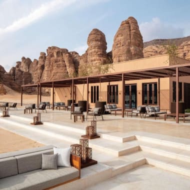 Luxurious outdoor lounge area with modern furniture and a shaded patio, set against a backdrop of distinctive sandstone rock formations.