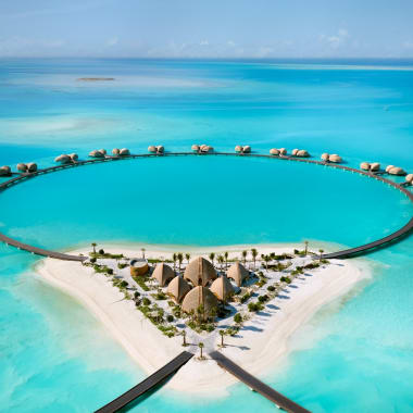 Luxushotel mit Wasserbungalows und einem großen kreisförmigen Pool am Strand am Roten Meer.