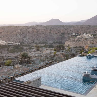 Luxury infinity pool overlooking a rocky mountainous landscape at sunset