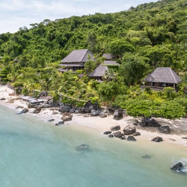 Luftaufnahme von Meer und Strand mit reed-gedeckten Bungalows im Regenwald