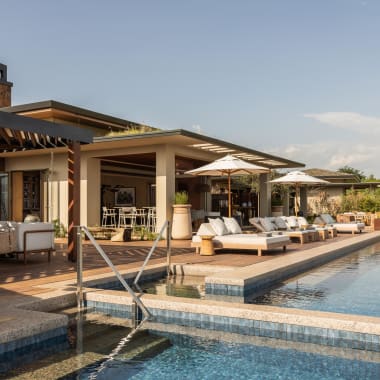 Luxurious outdoor poolside area at a resort with lounge chairs, umbrellas, and modern architecture.