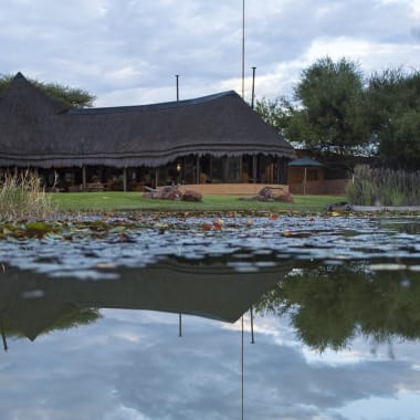 Aussenansicht des Okonjima Camps mit Teich im Vordergrund