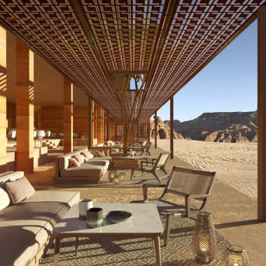 A covered terrace of the hotel with numerous seating areas overlooking the desert 