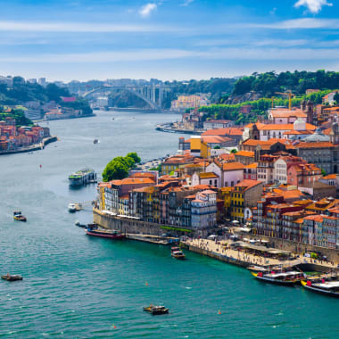 Panoramablick auf die Stadt Porto am Douro-Fluss mit bunten Gebäuden und Booten im Wasser.