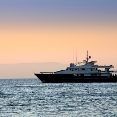 Luxusyacht, die bei Sonnenuntergang auf dem ruhigen Ozean vor den Galápagos-Inseln fährt.