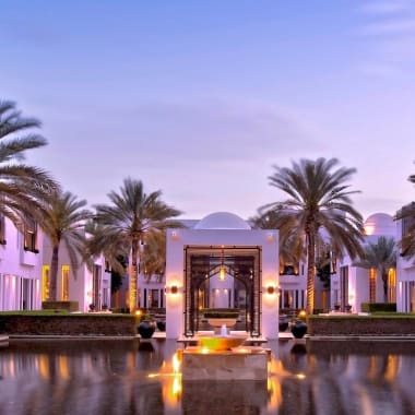 Ein luxuriöser Wasser-Garten-Hof mit Palmen und eleganter Architektur bei Sonnenuntergang.