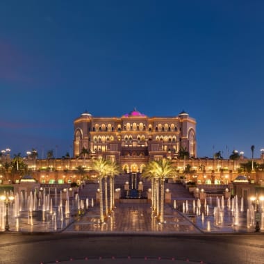 Nachtansicht des Emirates Palace Resorts in Abu Dhabi mit beleuchteten Brunnen im Vordergrund.