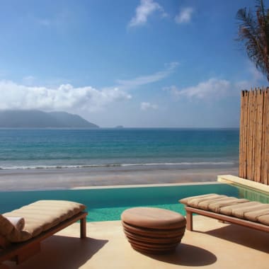 Blick von einer Luxusvilla mit Blick auf den Strand und das Meer, mit Liegen im Freien und einem Pool.