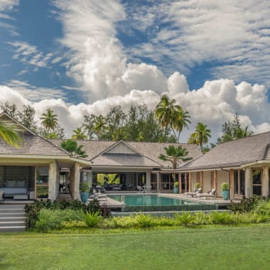 Luxuriöse dreizimmerige Präsidentenvilla im Four Seasons Resort Seychelles auf der Insel Desroches mit privatem Pool, umgeben von tropischer Vegetation unter einem wolkigen Himmel.
