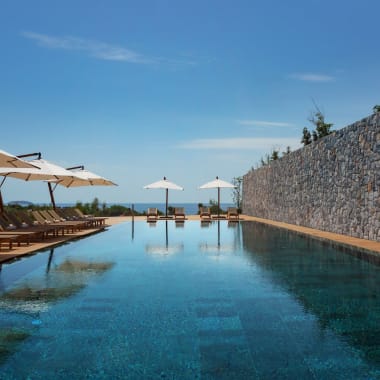 Luxury outdoor pool area with lounge chairs and umbrellas overlooking a scenic landscape in Turkey.