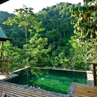 A wooden deck with a small pool overlooking lush green tropical forest in Costa Rica.